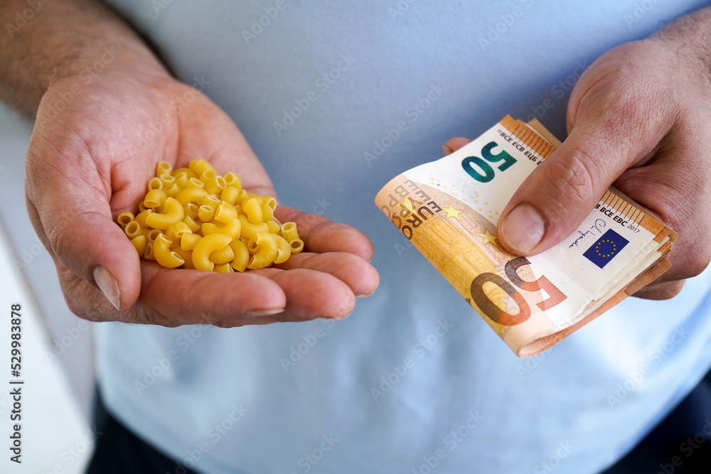 Obraz premium Close-up of the hands of a man holding a macaroni and euro bills in his hands.The concept of rising food prices, the global economic crisis.