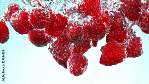 Raspberries pieces falling underwater on white background. #529984408