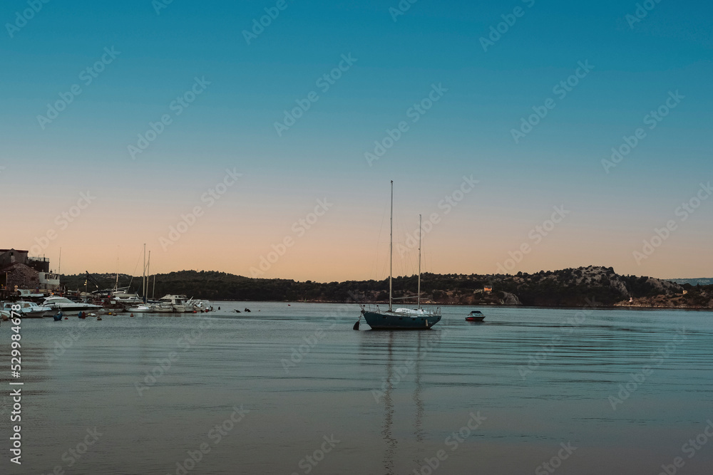 Boat in the sea against the backdrop of the seashore at sunset. Summer vacation travel concept
