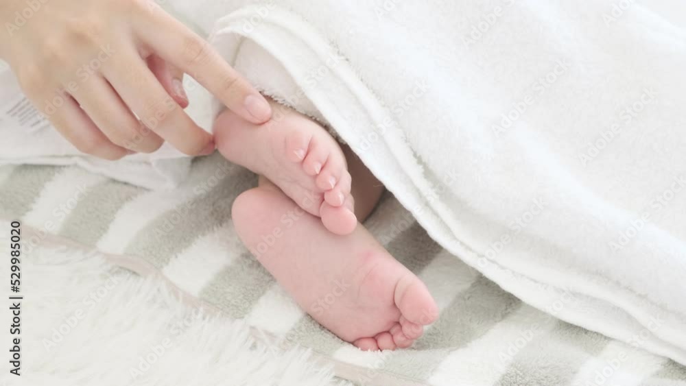 Mother plays with foot of her sleeping baby. Mother plays with foot of her sleeping baby.