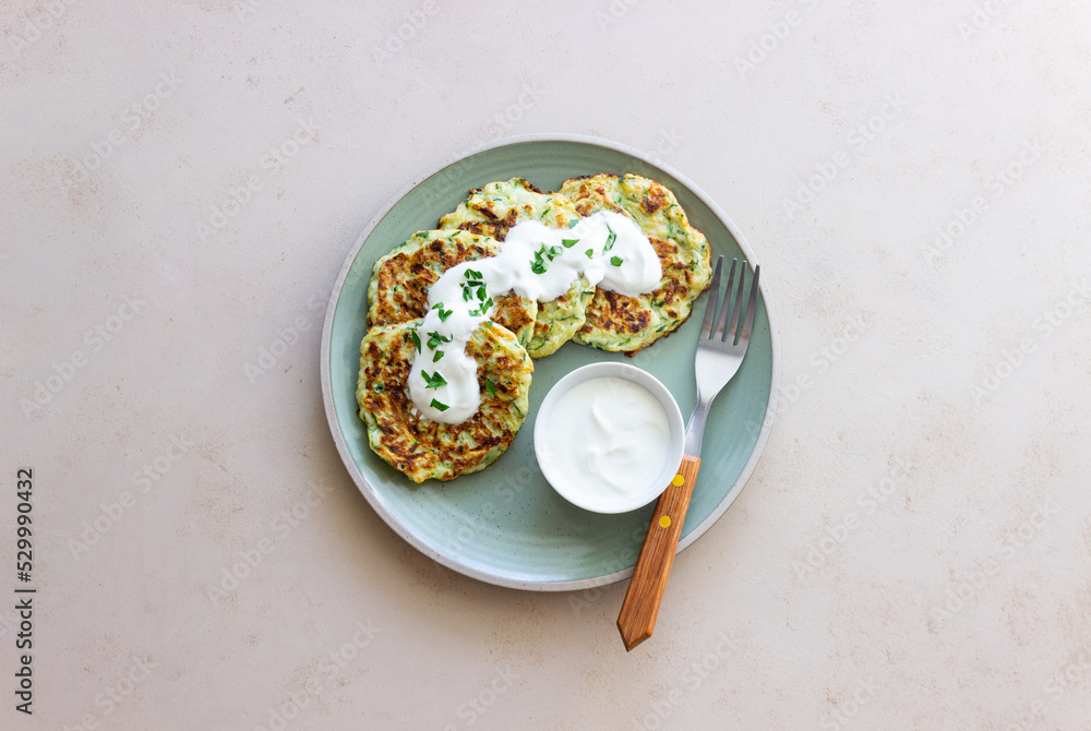 Zucchini fritters or pancakes with sour cream and herbs. Healthy eating. Vegetarian food. Zucchini fritters or pancakes with sour cream and herbs. Healthy eating. Vegetarian food.