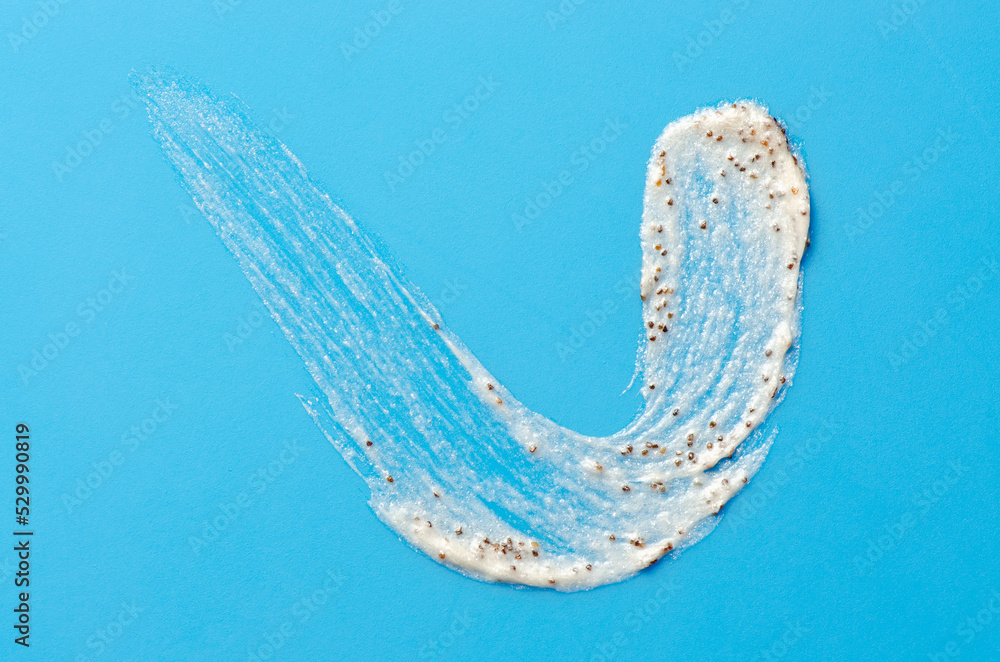A sample of a cosmetic skin scrub with apricot pits. Blue background. A sample of a cosmetic skin scrub with apricot pits. Blue background.