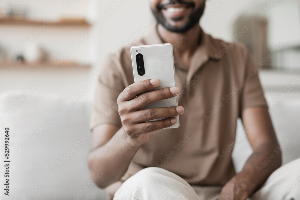 Young man using smartphone at home. Handsome man looking at mobile phone in his room. Communication, home work or study, connection, mobile apps, technology, lifestyle concept Young man using smartphone at home. Handsome man looking at mobile phone in his room. Communication, home work or study, connection, mobile apps, technology, lifestyle concept