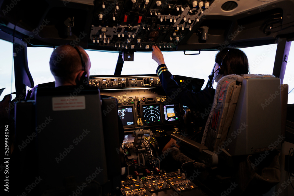 Woman copilot assisting captain to takeoff and fly airplane, using