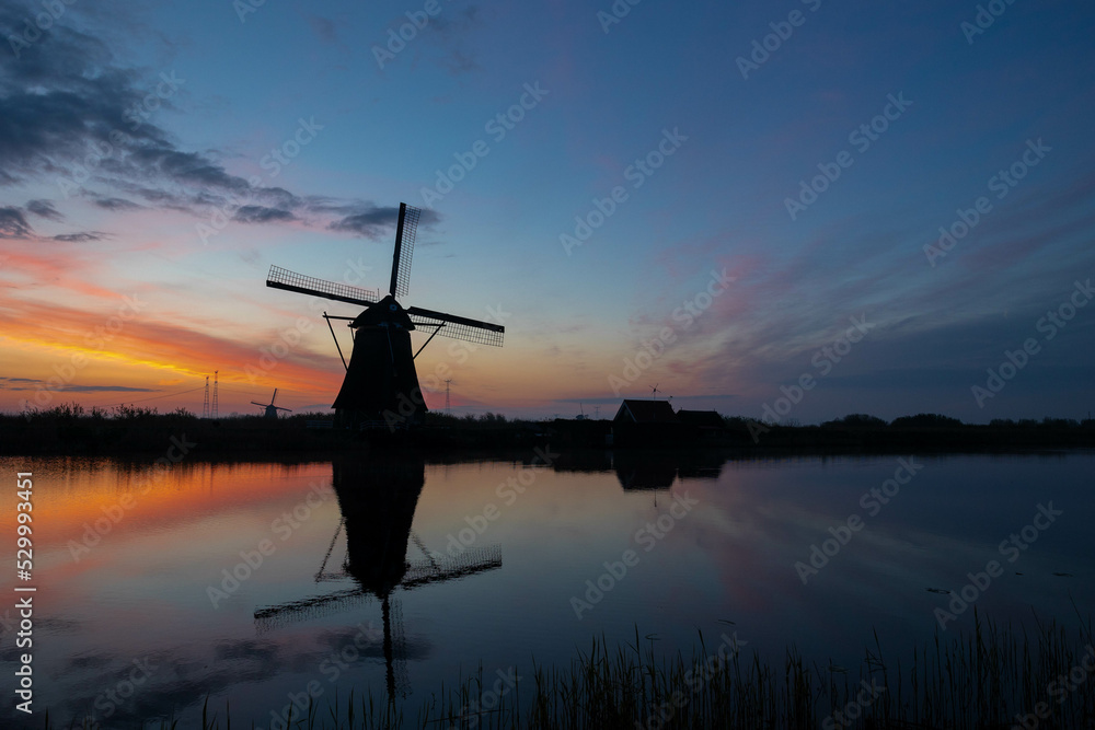silhouette of the windmills in kinderdijk during sunset, famous place in Holland, reflection in lake