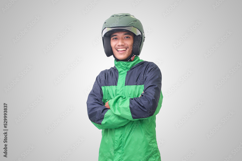 Portrait of Asian online taxi driver wearing green jacket and helmet, standing with crossed arms. Isolated image on white background Portrait of Asian online taxi driver wearing green jacket and helmet, standing with crossed arms. Isolated image on white background