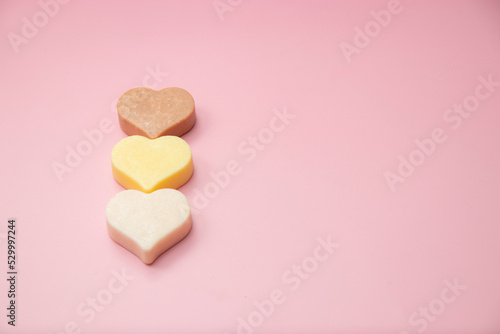 Heart shaped pink bar of soap on a light pink background. Top view, copy space. Heart shaped soaps. Importance of personal hygiene care. Copy space.