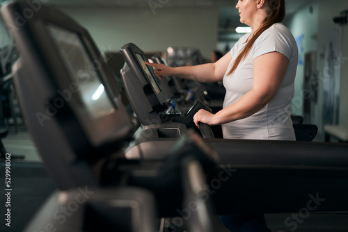 Part of plus size caucasian woman preparing for running on treadmill at gym