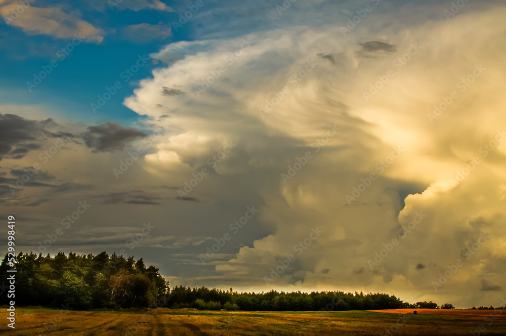 layered storm clouds, heavy rain clouds, landscape before sunset, spectacularly lit by sunlight