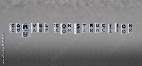 carvel construction word or concept represented by black and white letter cubes on a grey horizon background stretching to infinity photo