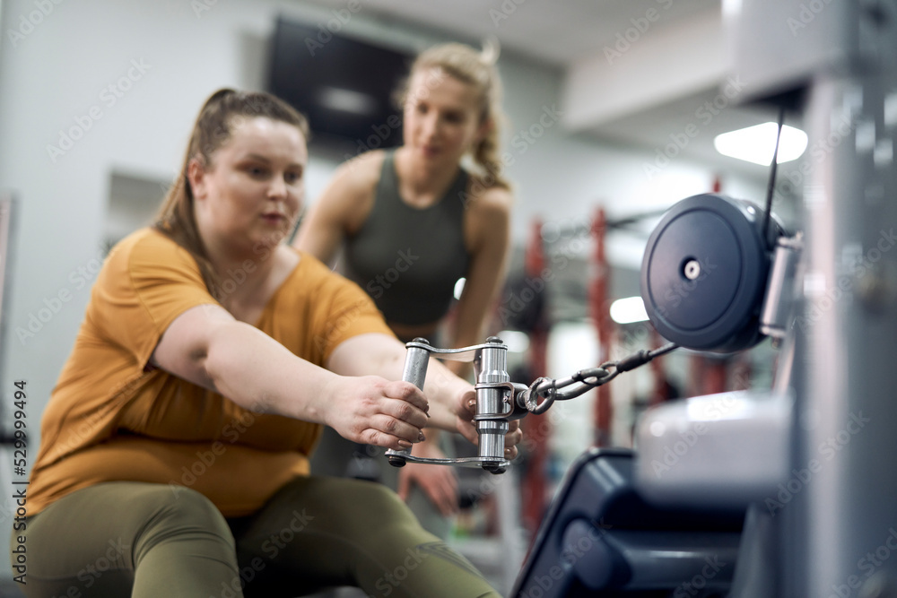 Caucasian plus size woman with her trainer at the gym Caucasian plus size woman with her trainer at the gym