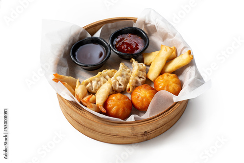 Oriental dumplings and shrimps in batter served with sauces served in a bamboo basket