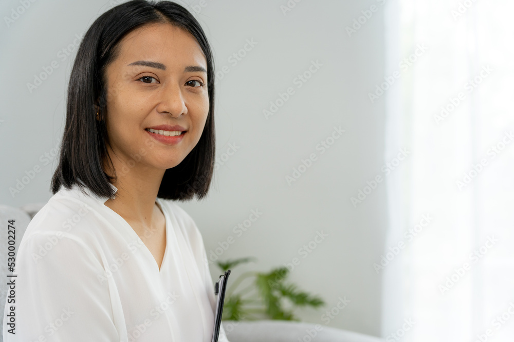 Asian businesswoman smiling and holding a book in office. Beautiful and good looking Asian woman sits on the sofa. female portraits. Asian businesswoman smiling and holding a book in office. Beautiful and good looking Asian woman sits on the sofa. female portraits.