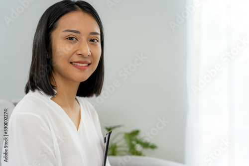 Asian businesswoman smiling and holding a book in office. Beautiful and good looking Asian woman sits on the sofa. female portraits. Free Download Asian businesswoman smiling and holding a book in office. Beautiful and good looking Asian woman sits on the sofa. female portraits. - GFXLoad