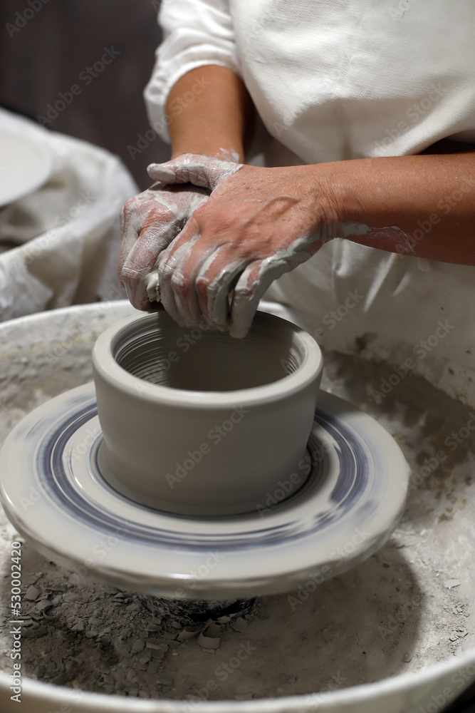 manos de artesana elaborando pieza de alfarería de cerámica en el torno