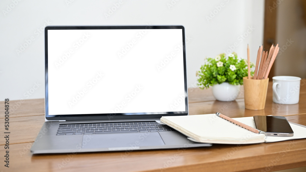 Workspace with notebook laptop mockup, spiral notebook, smartphone and decor on wood table Workspace with notebook laptop mockup, spiral notebook, smartphone and decor on wood table