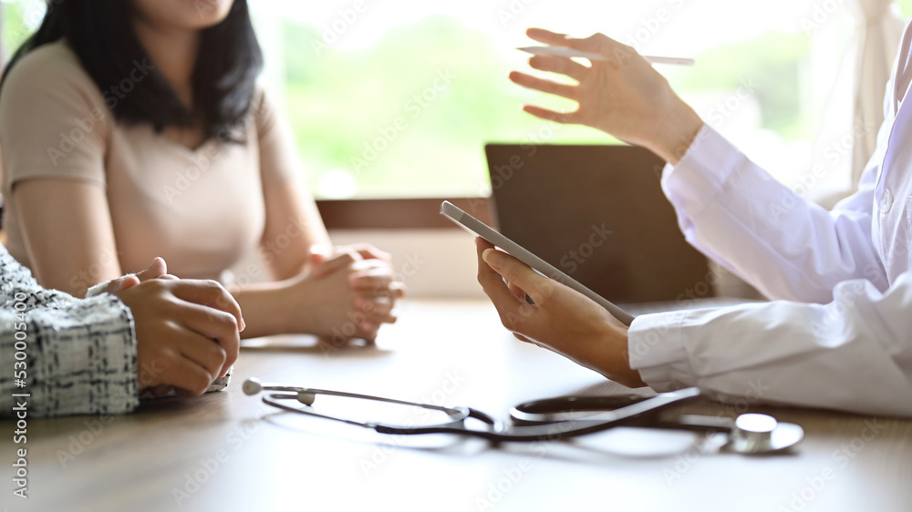 © bongkarn - A female doctor meets her patient in the office, asking for symptoms. cropped