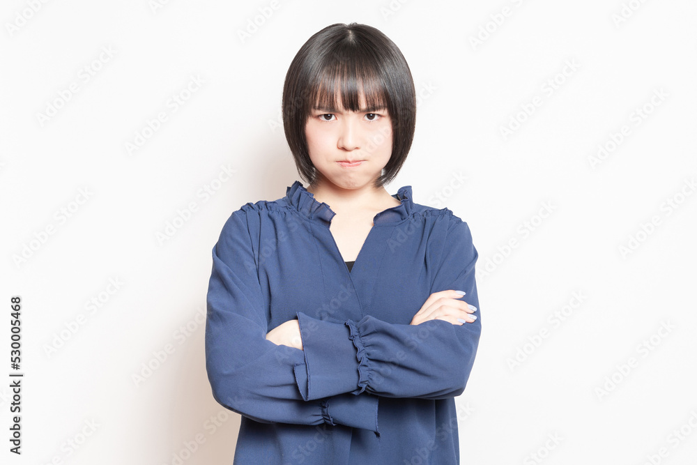 白背景の前に立って、怒っている若い女性