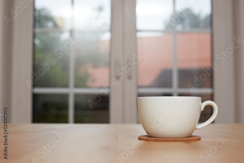 blurred background of kitchen and white cup of tea