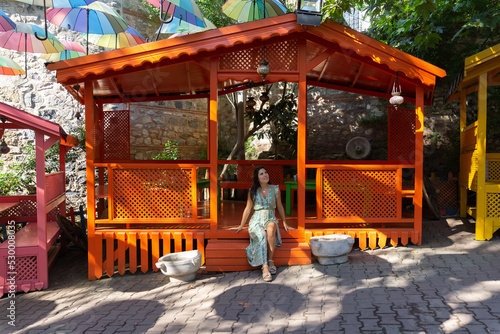 Young woman sitting in a wooden hut with colorful decorative umbrellas