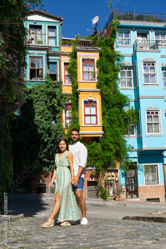 Canvas Print Young couple in love on an Istanbul street embracing and in the background colorful buildings with plants