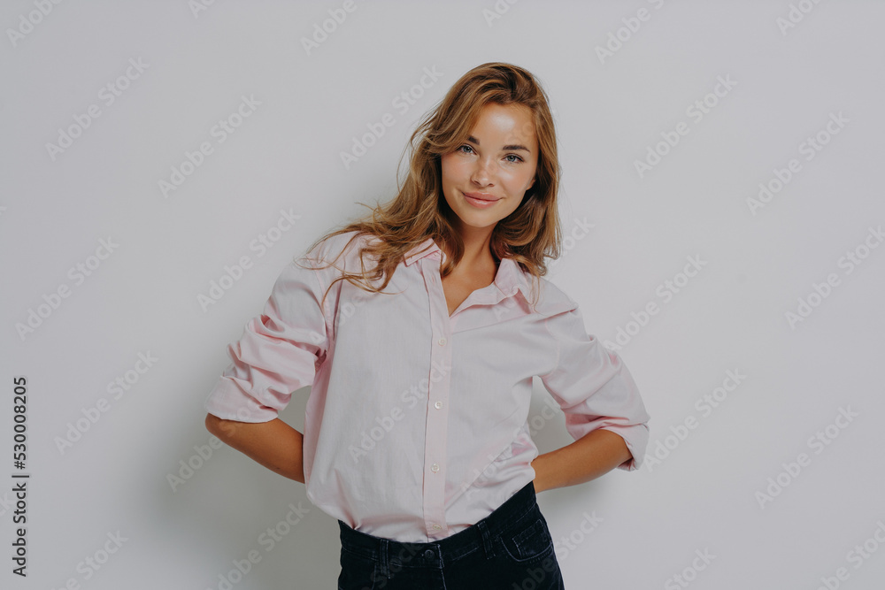 Elegant attractive female model in casual shirt and jeans standing with folded hands behind her back Elegant attractive female model in casual shirt and jeans standing with folded hands behind her back