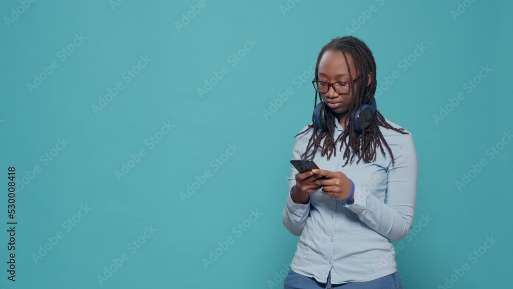 Young adult using smartphone to text messages in studio, browsing internet website on mobile phone. Scrolling through social media app on telephone, feeling relaxed and positive. Young adult using smartphone to text messages in studio, browsing internet website on mobile phone. Scrolling through social media app on telephone, feeling relaxed and positive.