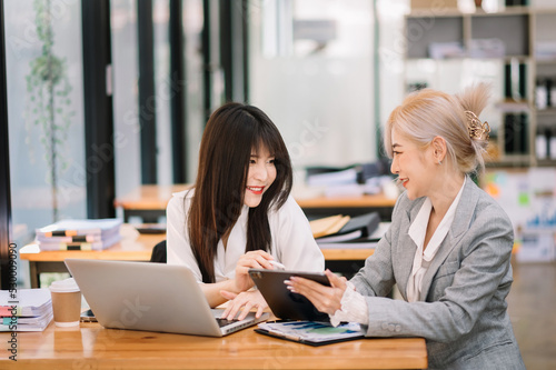 Wallpaper Mural Two Asian businesswoman discuss investment project working and planning strategy with tablet laptop computer in modern office.. Torontodigital.ca