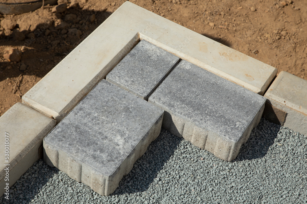 Laying gray concrete paving slabs in the courtyard of the house on a sandy foundation Laying gray concrete paving slabs in the courtyard of the house on a sandy foundation
