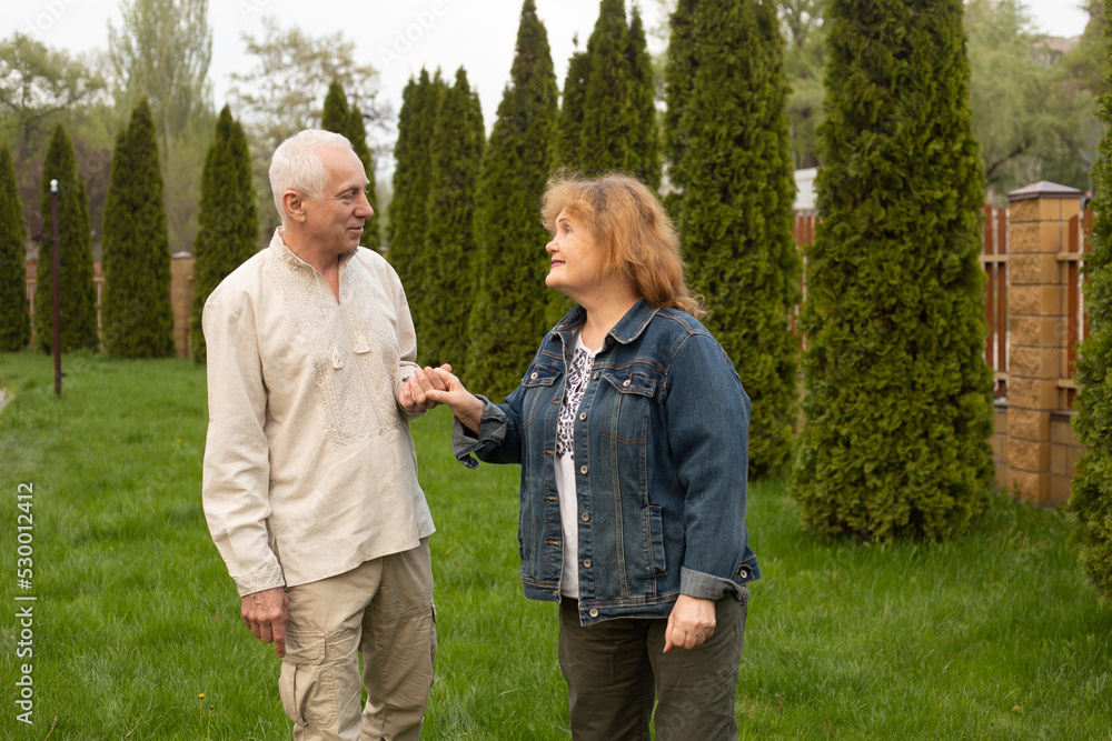 Senior couple embracing walking in autumn or summer park Senior couple embracing walking in autumn or summer park