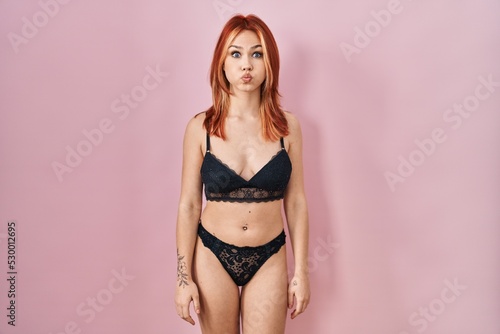 Young caucasian woman wearing lingerie over pink background puffing cheeks with funny face. mouth inflated with air, crazy expression.