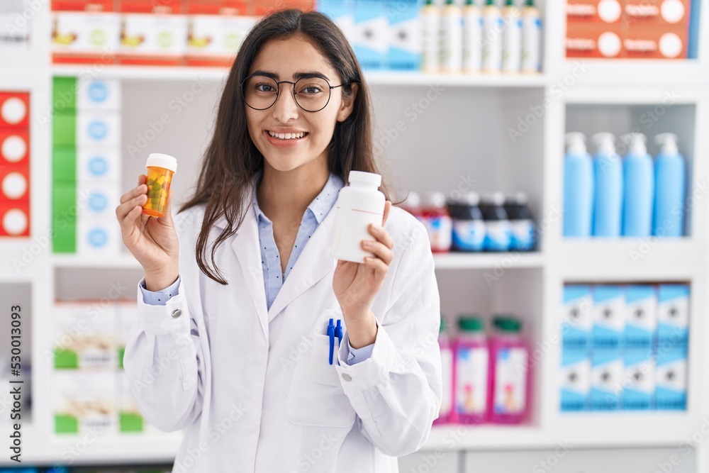 Young hispanic girl pharmacist choosing pills at pharmacy