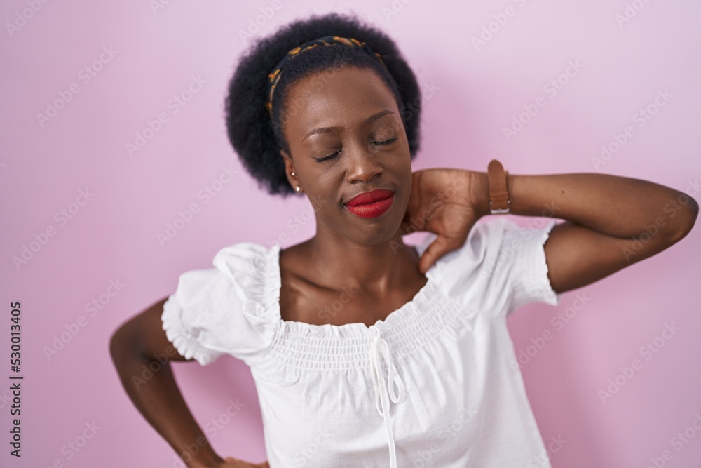 African woman with curly hair standing over pink background suffering of neck ache injury, touching neck with hand, muscular pain African woman with curly hair standing over pink background suffering of neck ache injury, touching neck with hand, muscular pain