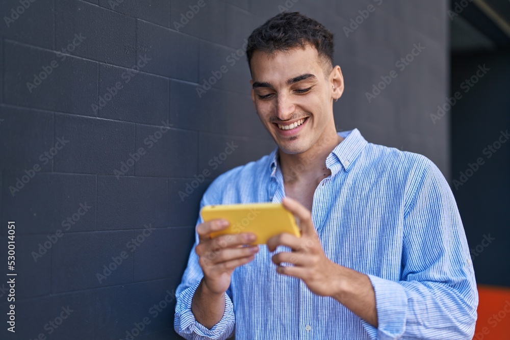 Young hispanic man smiling confident watching video on smartphone over black isolated background Young hispanic man smiling confident watching video on smartphone over black isolated background