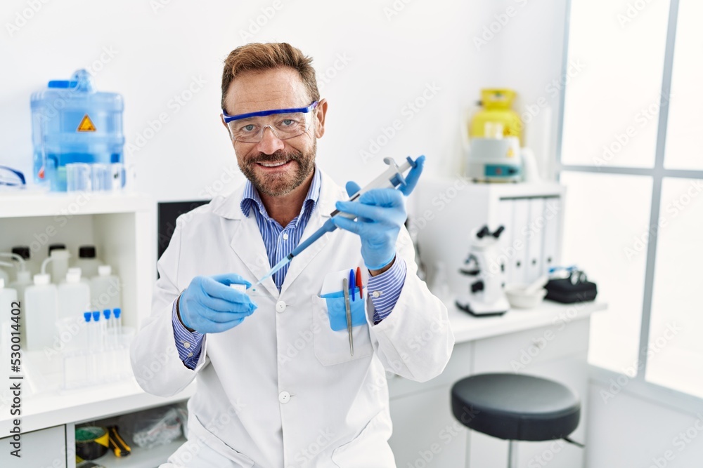Middle age hispanic man wearing scientist uniform working at laboratory Middle age hispanic man wearing scientist uniform working at laboratory
