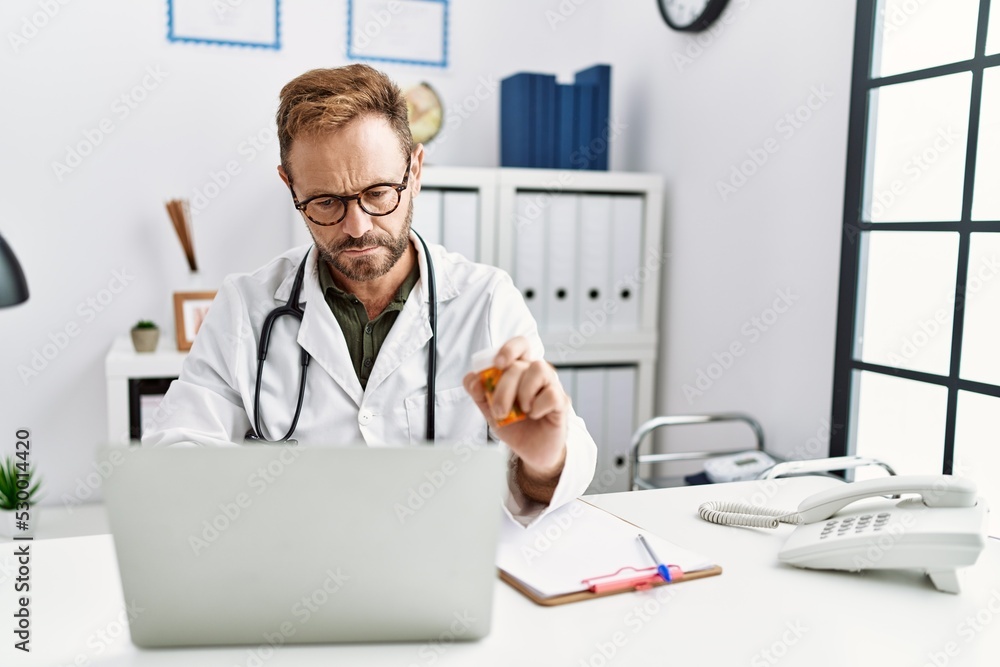 Middle age hispanic man wearing doctor uniform having video call at clinic