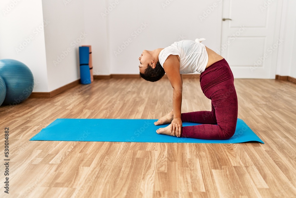 Young hispanic woman training yoga at sport center