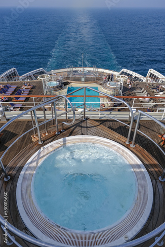 View from open outdoor deck of legendary luxury ocean liner cruise ship on passage during Transatlantic Crossing from Southampton to New York with deck chairs, railing and superstructure