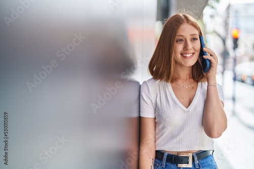 Young redhead woman smiling confident talking on the smartphone at street © Krakenimages.com