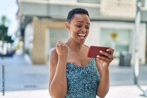 African american woman using smartphone with winner expression at street © Krakenimages.com