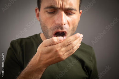  Man checks his breath with his hand. The concept of halitosis photo