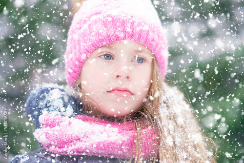 A thoughtful blond girl in pink hat in snowy weather.