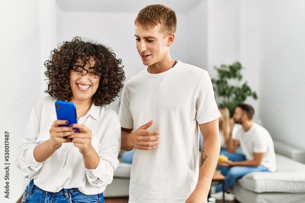 Fototapeta premium Two young friends standing and using smartphone at home.