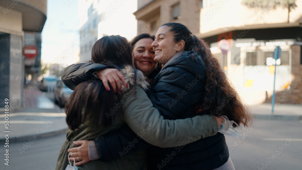 Fototapeta premium Mother and daugthers smiling confident hugging each other at street