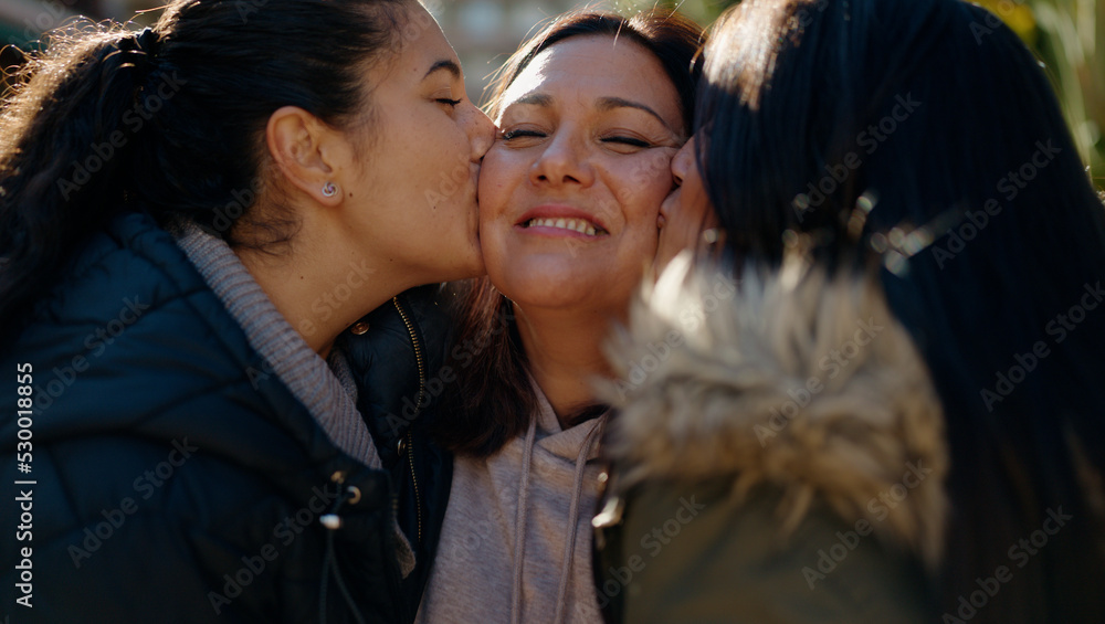Fototapeta premium Mother and daugthers kissing and hugging each other at park