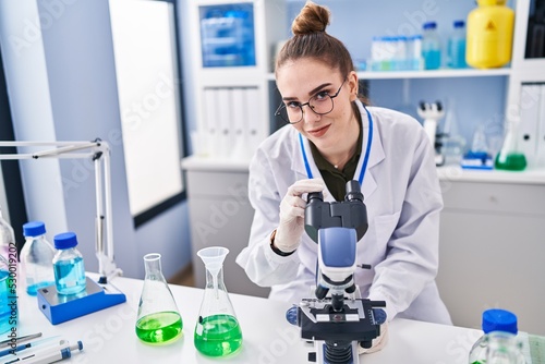 Young woman scientist using microscope at laboratory
