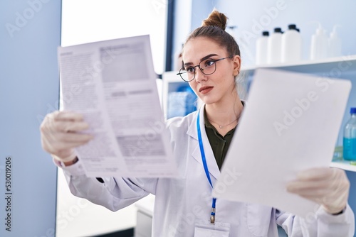 Young woman scientist reading document at laboratory