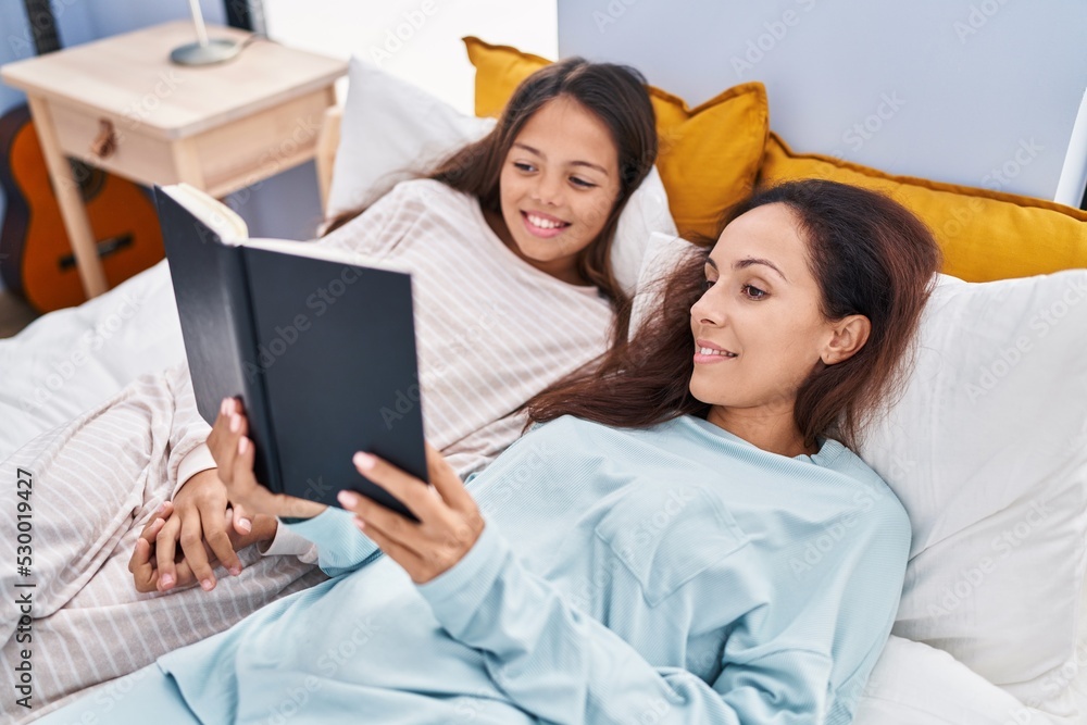 Woman and girl mother and daughter reading book at bedroom Woman and girl mother and daughter reading book at bedroom