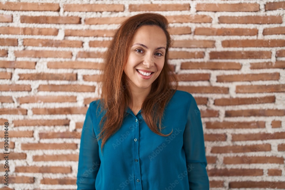 Brunette woman standing over bricks wall looking away to side with smile on face, natural expression. laughing confident. Brunette woman standing over bricks wall looking away to side with smile on face, natural expression. laughing confident.