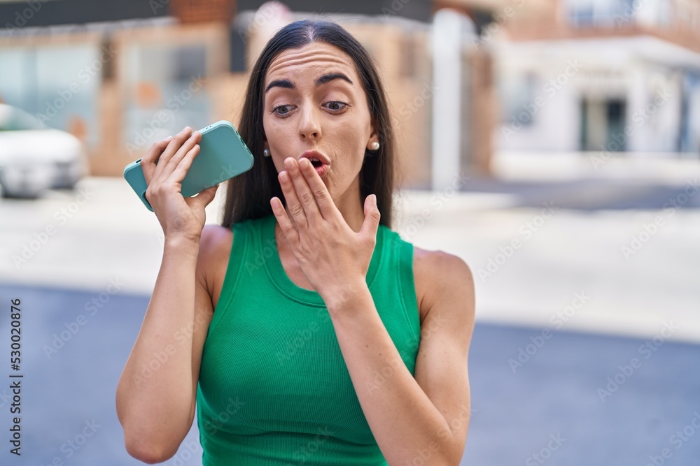 Young beautiful hispanic woman talking on the smartphone with surprise expression at street